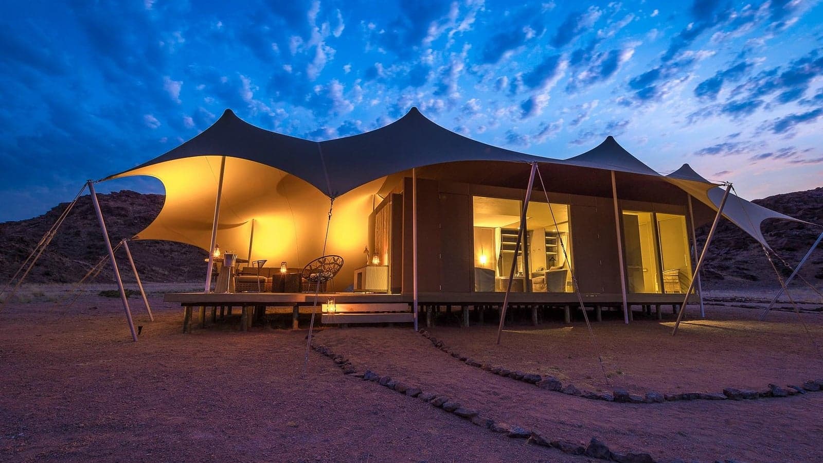 A tented suite lit at dusk at Hoanib Skeleton Coast Camp