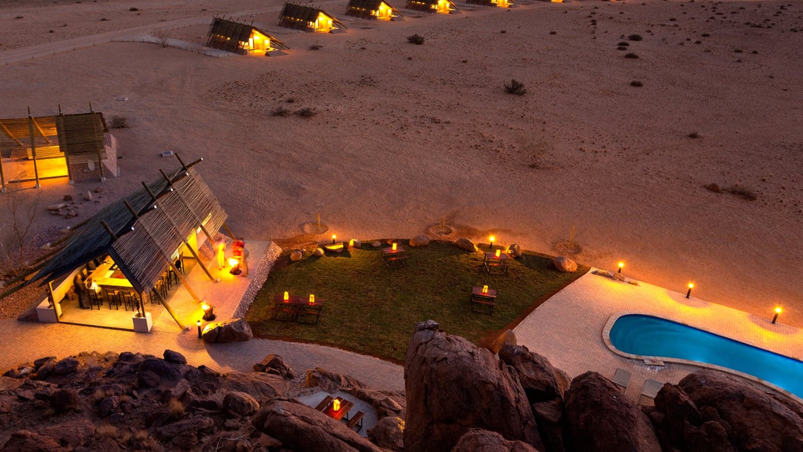 Thatched self-catering chalets on red desert terrain at Desert Quiver Camp, Sossusvlei