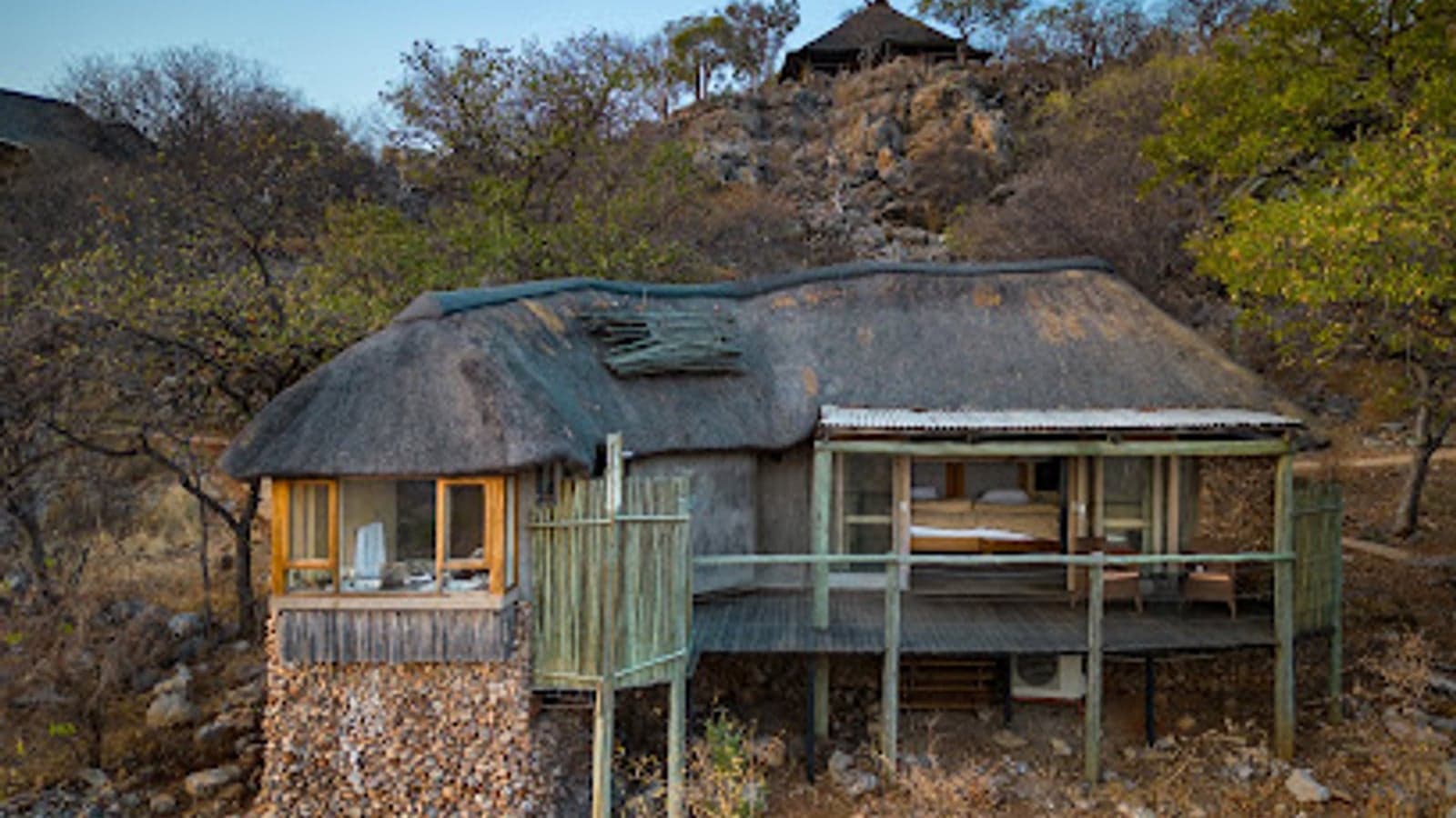 Chalet in paglia costruito contro uno sperone roccioso a Ongava Lodge, Etosha
