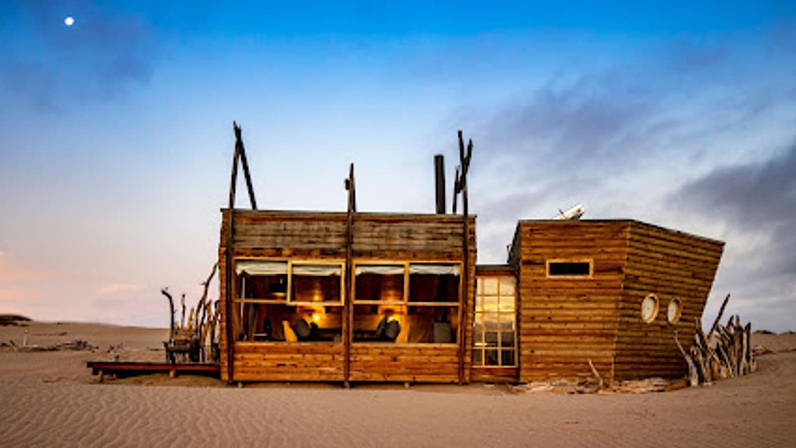 The shipwreck-shaped chalets of Shipwreck Lodge on the dunes at dusk